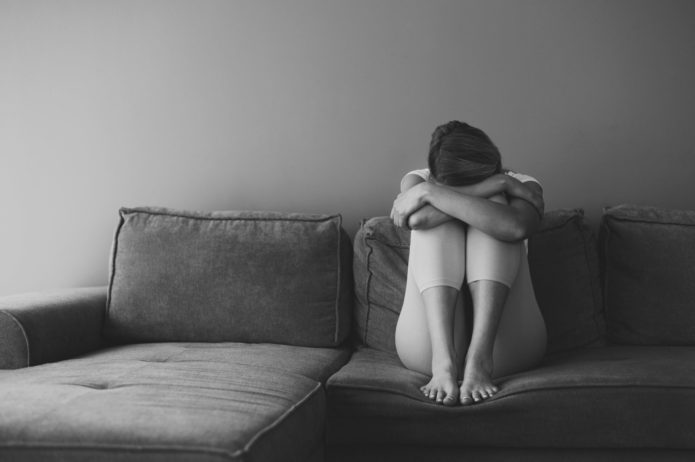 l1vHKpyr-full-shot-woman-sitting-couch-695×462